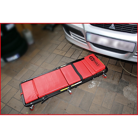 Cric de garage rouge devant une voiture grise.